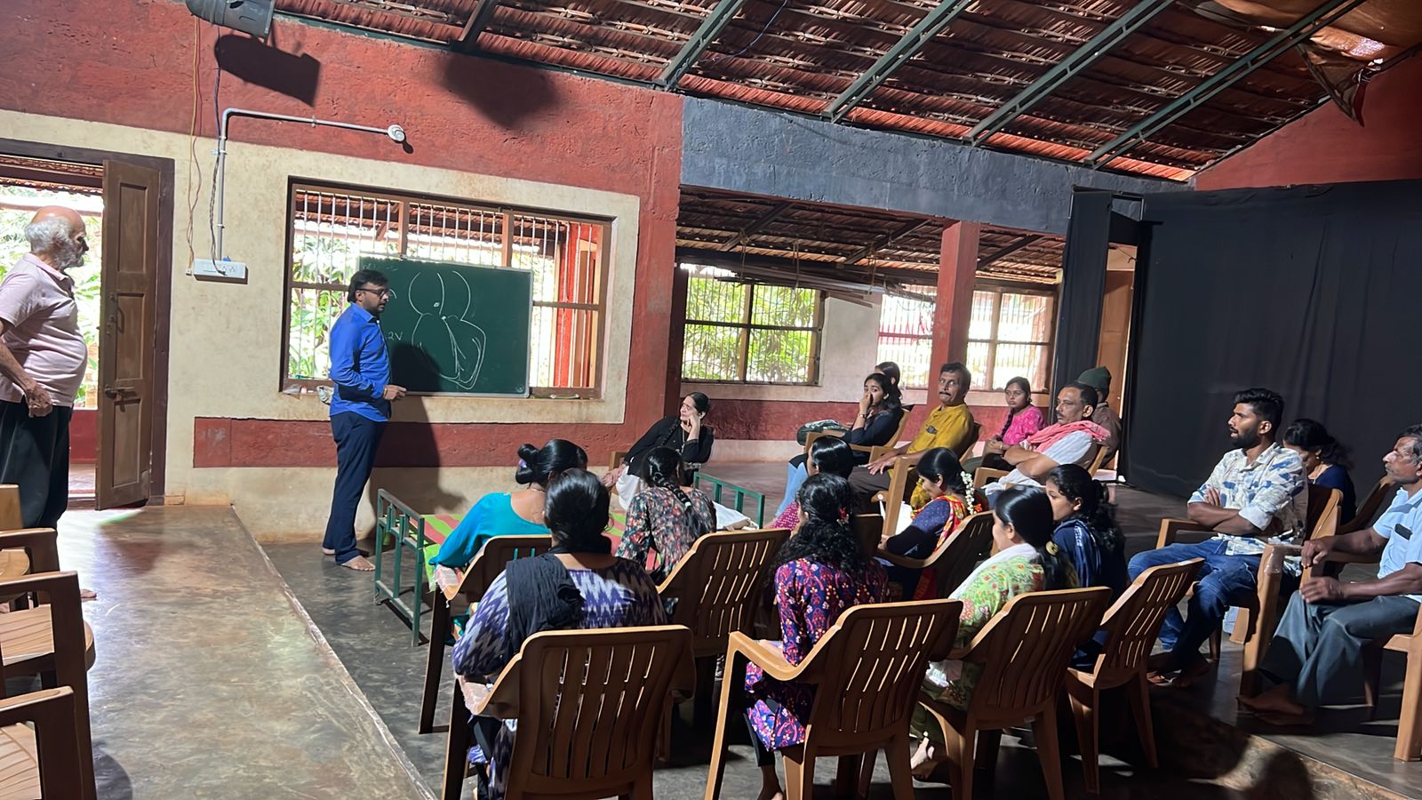 A health educator speaking with community members in a rural hall